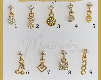 Könnte beinhalten: Neun 925er Sterling Silber Ohrringe mit verschiedenen Anhängern. Die Anhänger umfassen einen Kreis, ein Unendlichkeitszeichen, eine Sternform, eine Träne, eine Kirsche, ein Quadrat und eine Kette.