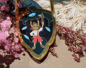 Puede incluir: Pin de esmalte de color dorado con un personaje de dibujos animados sosteniendo una espada, de pie frente a un escudo negro con ojos azules.