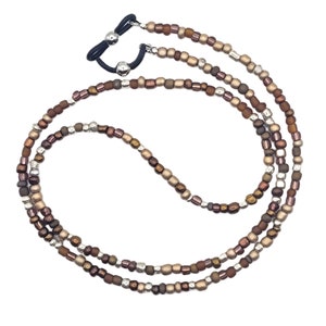 May include: A triple-strand beaded glasses chain with brown, gold, and silver beads. The chain has a black elastic band with a silver clasp.