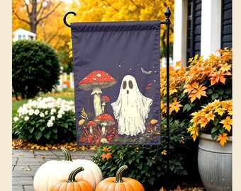 May include: A rectangular garden flag featuring a dark purple background with a white ghost standing next to several red and white spotted mushrooms. The illustration includes small stars and a moth, all set against a dark, atmospheric forest floor.