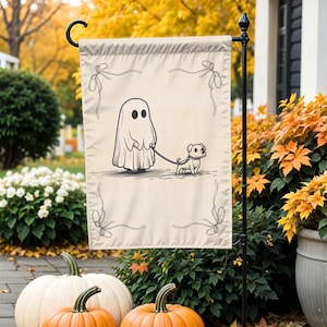 May include: A beige Halloween garden flag features a whimsical illustration of a ghost walking a dog on a leash. The black and white design is framed with decorative bows. Pumpkins and fall foliage are in the background.