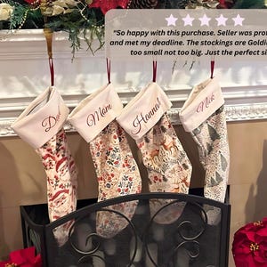 Customer photo of personalized family Christmas stockings with custom names hanging from a festive fireplace mantel, showing the velvet stockings styled in a real home.