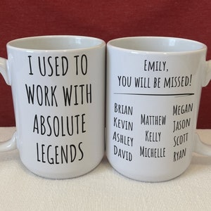 May include: Two white ceramic mugs with black text. The left mug reads I USED TO WORK WITH ABSOLUTE LEGENDS. The right mug reads Emily, YOU WILL BE MISSED! followed by a list of names including Brian, Kevin, Ashley, David, Matthew, Kelly, Michelle, Megan, Jason, Scott, and Ryan.