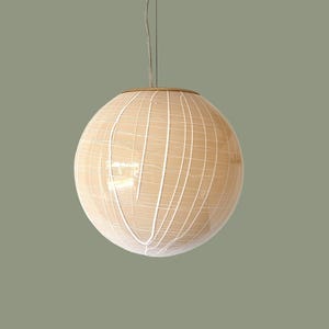 May include: A beige globe pendant light with a white grid pattern. The light fixture hangs from a thin wire and has a gold-colored rim. The spherical lamp is a decorative lighting element.