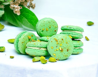 Puede incluir: Primer plano de una pila de macarons verdes con relleno de pistacho. Los macarons están decorados con pistachos picados.
