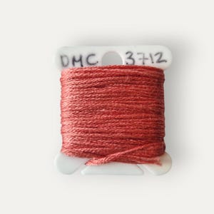 May include: A spool of DMC 3712 embroidery thread in a reddish-brown colour. The thread is tightly wound on a white plastic spool. The text "DMC 3712" is printed on the spool. The words "Bailey Whin Supplies" are printed below the spool.