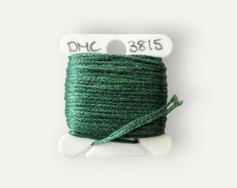May include: A spool of DMC embroidery floss in a dark green color. The spool is labeled with the DMC number 3815.