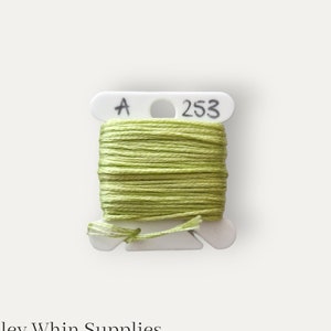 May include: A spool of light green embroidery floss labelled "A 253" on a white plastic bobbin.