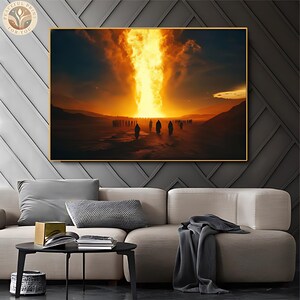 Könnte beinhalten: Ein gerahmter Kunstdruck zeigt eine dramatische Szene eines feurigen Pfeilers, der von einem Sonnenuntergangshimmel auf eine Wüstenlandschaft herabsteigt. Silhouetten gehen auf das Licht zu. Das Kunstwerk wird über einem beigen Sofa mit grauen Kissen ausgestellt.