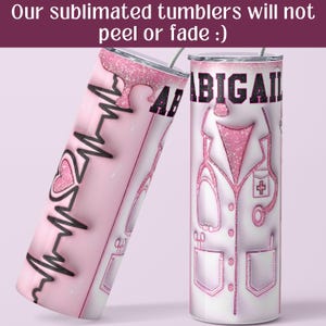 May include: Pink and white stainless steel tumbler with a pink glitter design. The tumbler has a black and white heart beat design on one side and the name "ABIGAIL" and a pink glitter doctor's coat design on the other side.