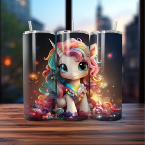 May include: A set of three stainless steel tumblers with a whimsical unicorn design. The unicorn has a white body, a rainbow mane and tail, and a colorful outfit. Each tumbler has a clear straw and a black background.