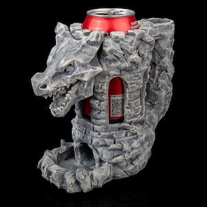 May include: A grey stone dragon head with a stone tower on its back. The tower has a slot for a can, and a can of soda is in the slot. The dragon's mouth is open, and its eyes are black.