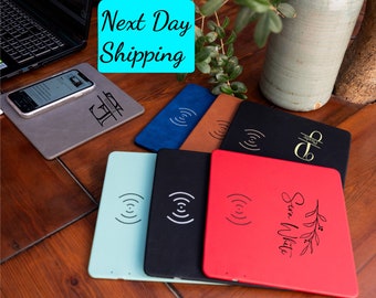 May include: Six different wireless charging pads with various colours and personalised engravings. The pads are made of a soft, leather-like material and feature a wireless charging symbol. The pads are arranged in a row on a wooden surface.