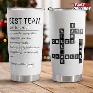 May include: White stainless steel tumbler with the text "BEST TEAM" and a definition. The other side has a crossword puzzle with names. The tumbler has a silver rim and a black lid. The words "FAST DELIVERY" are in the top right corner.