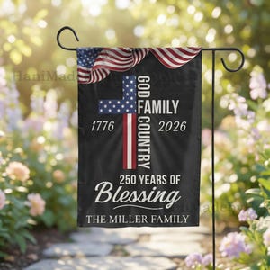 Op de afbeelding: Een zwarte tuinvaandel met een Amerikaans vlagontwerp en de tekst "GOD, FAMILY, COUNTRY" in het wit. De vlag bevat ook de tekst "1776 2026" en "250 YEARS OF Blessing". De onderkant van de vlag luidt "THE MILLER FAMILY".