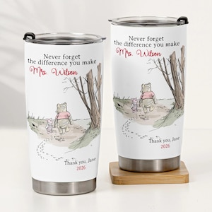Könnte beinhalten: Zwei weiße Reisebecher mit schwarzen Deckeln. Jeder Becher zeigt eine Winnie-the-Pooh-Illustration mit dem Text "Never forget the difference you make Mrs. Wilson" und "Thank you, Jane 2026".