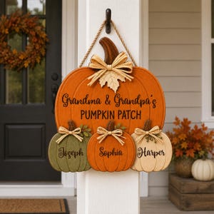 May include: A wooden pumpkin-shaped door sign featuring a large orange pumpkin with the text Grandma & Grandpa's PUMPKIN PATCH, and three smaller hanging pumpkins in green, orange, and cream, personalized with the names Joseph, Sophia, and Harper.