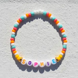 Pulseira de contas coloridas com nome e letras de acrílico multicoloridas
