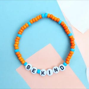 Soyez gentil·le - Bracelet de perles inspiré de Lando Norris en Formule 1. Bracelet de perles orange et bleues sur élastique, motif Formule 1.