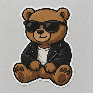 Puede incluir: Ilustración de un oso de peluche marrón con gafas de sol negras y una chaqueta de cuero negra sobre una camiseta blanca. El oso está sentado con las piernas cruzadas y tiene una expresión sonriente. La pegatina tiene un borde blanco.