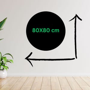 May include: A black circle with the text "80X80 cm" in green, with black arrows indicating dimensions. The image is on a white wall with a wooden floor and a potted plant in the corner.
