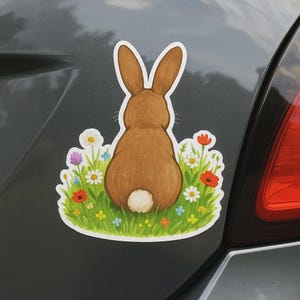 Adesivo per camper, laptop o auto raffigurante un coniglio su un prato fiorito. Delicato motivo animale come regalo per gli amanti del giardino e per i bambini.
