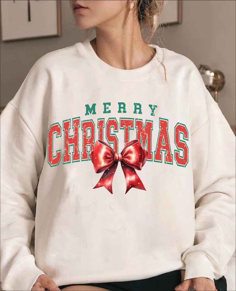Puede incluir: Sudadera blanca con un gr&aacute;fico vintage rojo y verde que dice "Merry Christmas" con un lazo rojo.