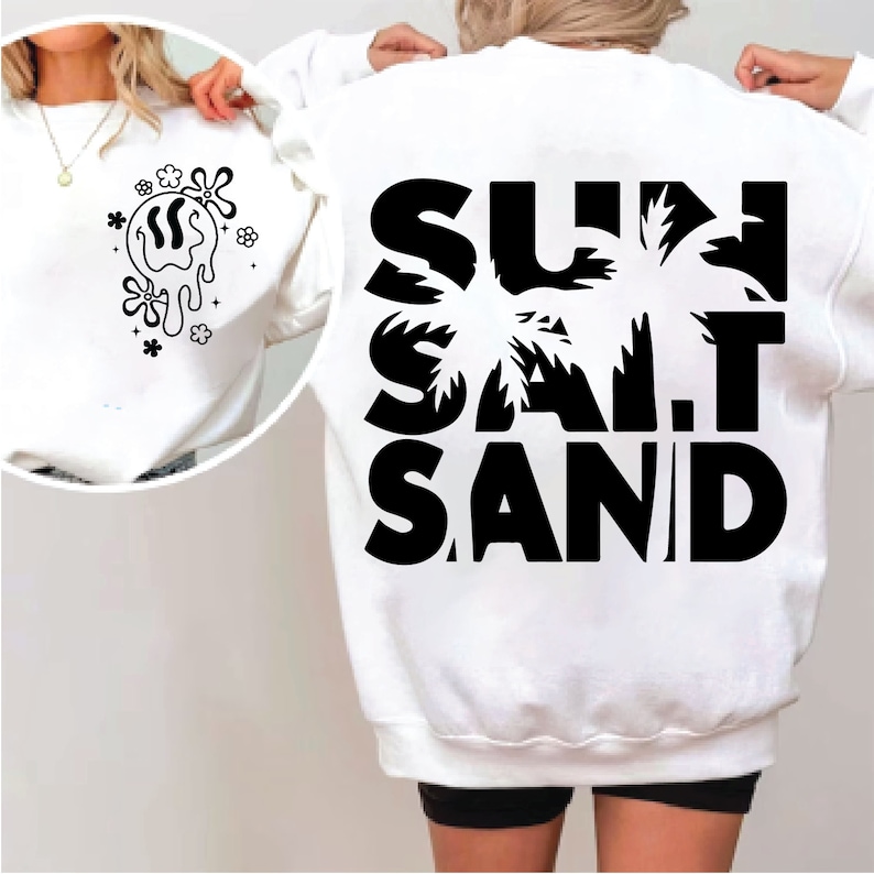 以下が含まれることがあります： 黒文字で「SUN SALT SAND」と書いてある白いスウェットシャツ。ヤシの木のグラフィックが描かれています。