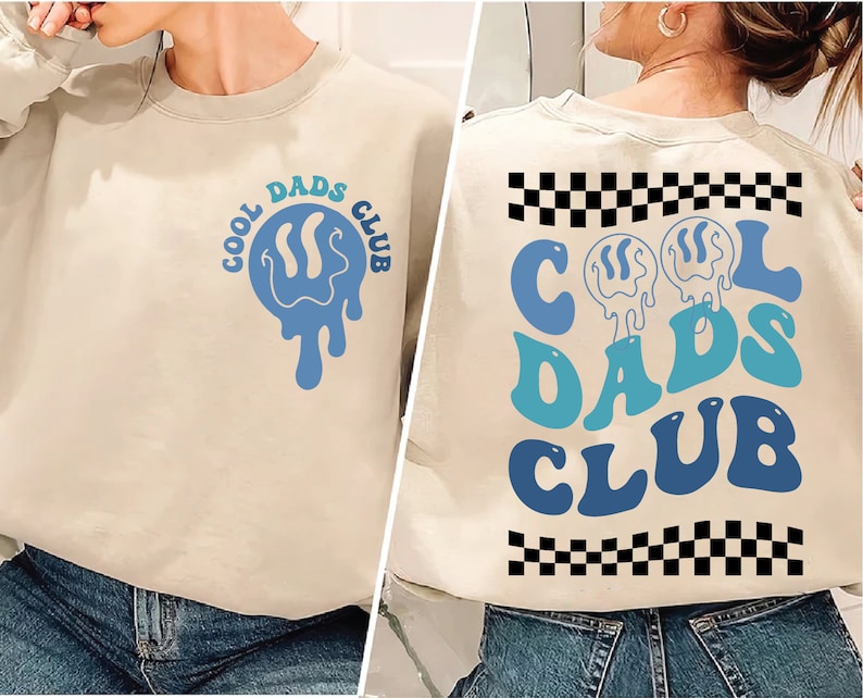 May include: A beige sweatshirt with a blue and green "Cool Dads Club" graphic on the front and a blue and green "Cool Dads Club" graphic with a black and white chequered pattern on the back.