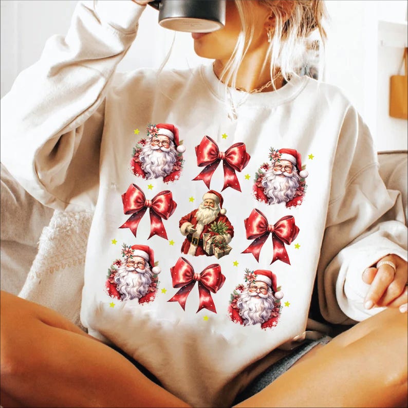 Puede incluir: Sudadera blanca con un dise&ntilde;o navide&ntilde;o festivo con m&uacute;ltiples im&aacute;genes de Pap&aacute; Noel y lazos rojos.