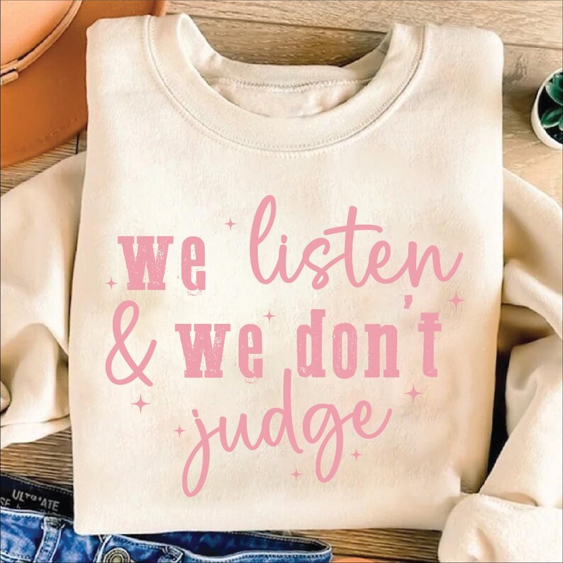 May include: A beige sweatshirt with the text "We listen & We don't judge" in pink lettering.