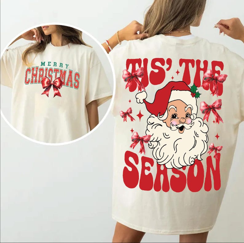 May include: A white t-shirt with a red and green "Merry Christmas" graphic on the front and a red and white "Tis' the Season" graphic with a cartoon Santa Claus on the back.