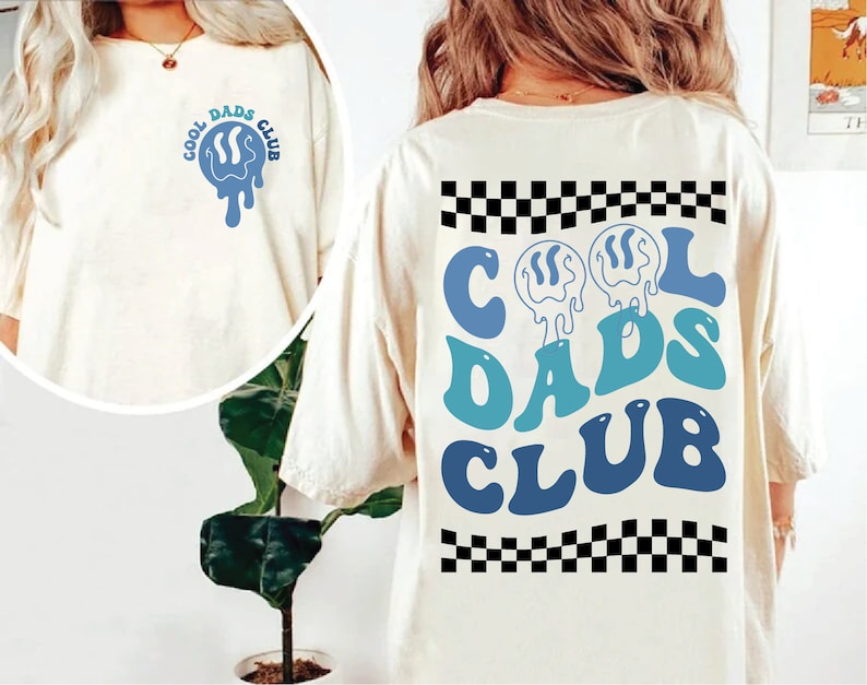 May include: White t-shirt with a blue and white graphic that says "Cool Dads Club" on the front and back. The graphic on the back is larger and has a checkered pattern at the top and bottom.