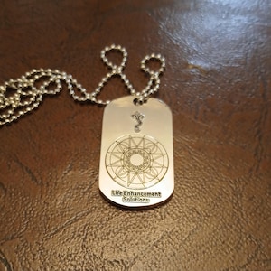 May include: Silver dog tag necklace with a geometric design and the text "Life Enhancement Solutions".