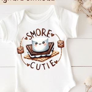 May include: White baby onesie with a brown, white, and tan illustration of a s'more with the text "SMORE CUTIE" and hearts.