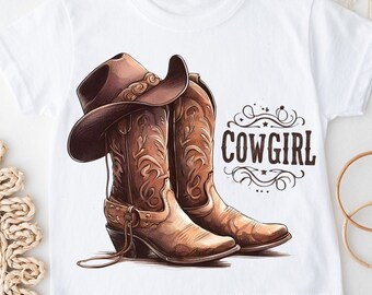 May include: White t-shirt with a brown cowboy hat and boots illustration. The text "COWGIRL" is printed on the shirt.