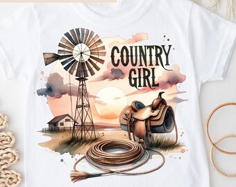 May include: White t-shirt with a watercolor design of a windmill, sunset, saddle, and rope. The text "COUNTRY GIRL" is printed on the shirt.