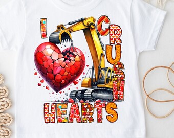 May include: A white t-shirt with a yellow excavator digging into a red heart. The text "I Crush Hearts" is written in red and orange letters.