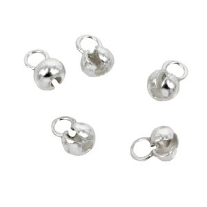 May include: Five small, silver-coloured bead caps are shown. Each cap has a rounded, hollow shape with a small loop at the top and a slit on the side. These components are used in jewellery making to finish the ends of beads or strands.