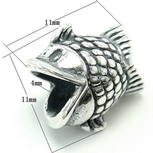 Può includere: Ciondolo in argento a forma di pesce con la bocca aperta. Il ciondolo è lungo 11 mm e largo 4 mm.