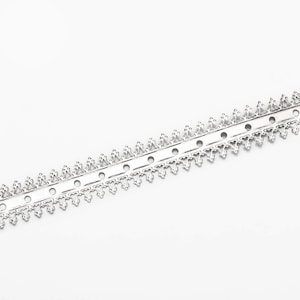 May include: A silver metal trim featuring a repeating heart and triangle design along its edge. The trim has small, evenly spaced circular holes. The symmetrical design is set against a white background.