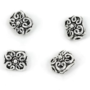 May include: Four silver-toned metal spacer beads with a decorative floral design. Each bead has a raised center and intricate scrollwork.