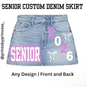 Könnte beinhalten: Hellblauer Jeansrock mit dem Wort "SENIOR" in rosa Blockbuchstaben. Der Rock hat die Zahlen "2026" in Rosa und weiße Schleifen. Der Text "SENIOR CUSTOM DENIM SKIRT" steht oben.