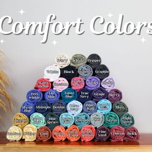 May include: A pyramid of rolled fabric swatches in various colors, including white, black, blue, green, and red. The swatches are labeled with color names, such as "Ivory", "Khaki", "Pepper", "White", "Black", "Granite", "Graphite", "Watermelon", "Blossom", "Crunch Berry", "Violet", "Orchid", "Peri Winkle", "Flo Blue", "Topaz Blue", "True Navy", "Grape", "Berry", "Mystic Blue", "Midnight", "Denim", "Cham Bray", "Blue Jean", "Lagoon Blue", "Moss", "Island Reef", "Blue Spruce", "Chalky Mint", "Seafoam", "Bay Grass", "Light Green", "Banana", "Butter", "Yam", "Melon", "Burnt Orange", "Bright Salmon", "Vine Yard", "Crimson", and "Brick".
