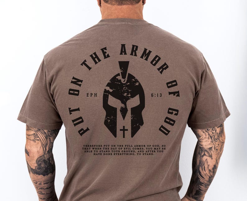 May include: A brown t-shirt with a black graphic of a helmet and the text "Put on the Armor of God" with the scripture reference "Eph 6:13".