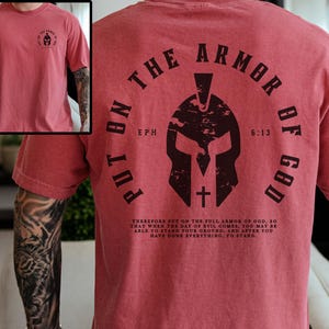 May include: Red t-shirt with a graphic of a helmet and the text "Put on the Armor of God, Eph 6:13". The text is in a black circle with a white cross inside the helmet.