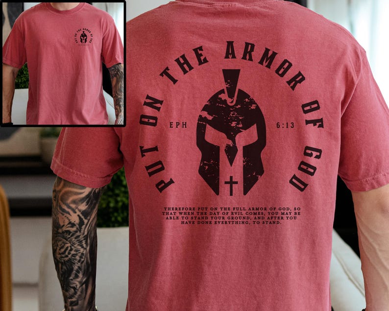 May include: Red t-shirt with a graphic of a helmet and the text "Put on the Armor of God, Eph 6:13". The text is in a black circle with a white cross inside the helmet.
