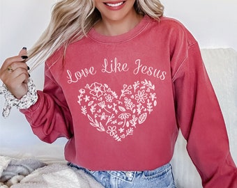 Może przedstawiać: Czerwona bluza z białym kwiatowym wzorem serca i napisem "Love Like Jesus".
