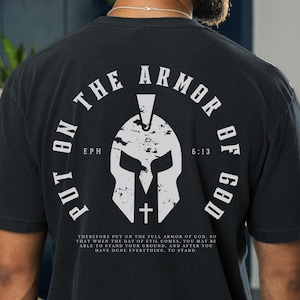 May include: Black t-shirt with a white graphic of a Spartan helmet and the text "Put on the Armor of God" with the scripture reference "Eph 6:13".