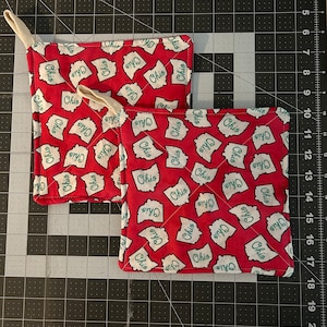 May include: Two red fabric pot holders with a white background and green "Ohio" text printed on them. The pot holders have a loop handle.